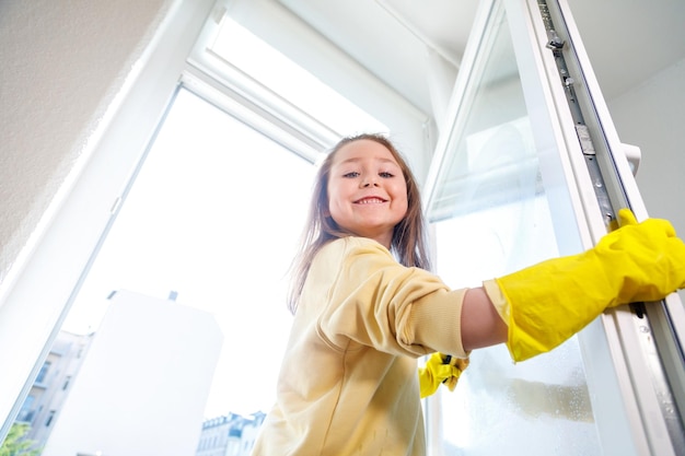 Schattig klein meisje helpt ouders met het raam schoonmaken in de lente