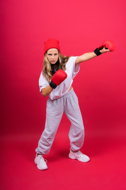 Schattig klein meisje in bokshandschoenen op rode achtergrond studio