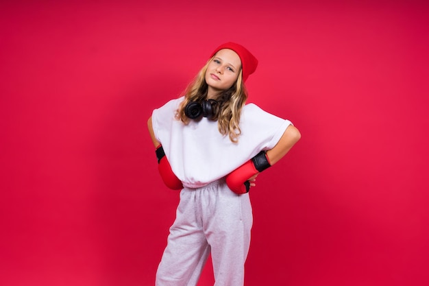Schattig klein meisje in bokshandschoenen op rode achtergrond studio