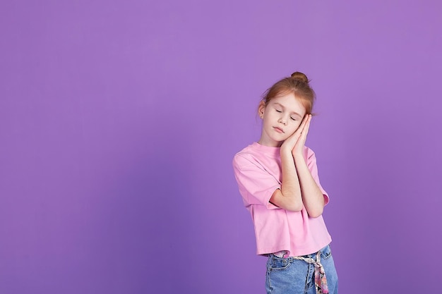 Schattig klein meisje in de studio op een lila achtergrond glimlachend en kijkend naar de camera