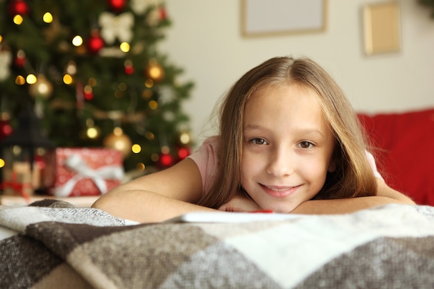 Schattig klein meisje in het kerstinterieur van het huis