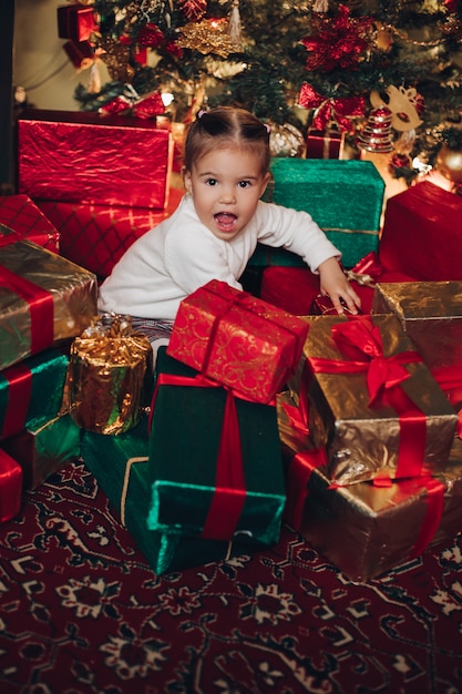 Schattig klein meisje in kerstcadeautjes. Kerstboom.