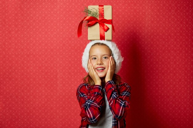 Schattig klein meisje in kerstmuts met een kerstcadeau op haar hoofd