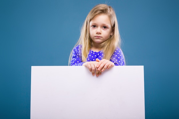 Schattig klein meisje in paarse jurk houdt lege poster