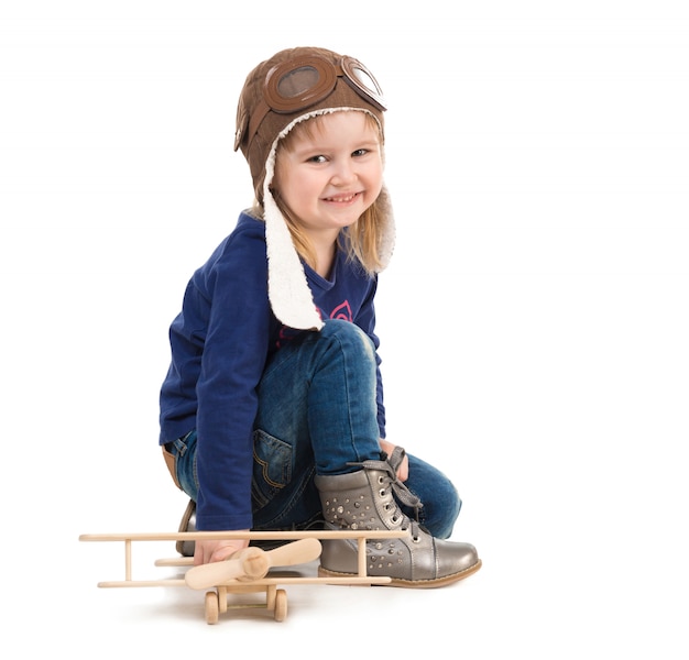 Schattig klein meisje in piloot hoed met houten vliegtuig