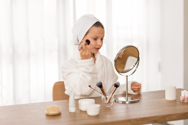 Schattig klein meisje in witte badjas make-up thuis aanbrengen