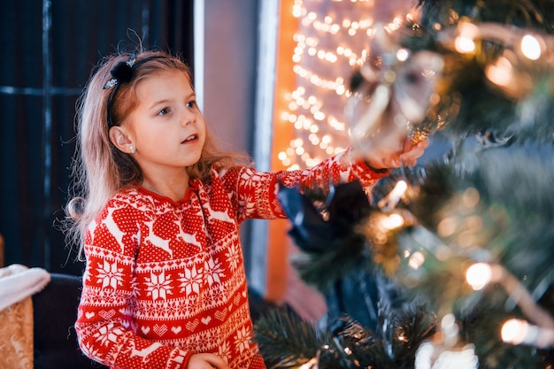 Schattig klein meisje kerstboom binnenshuis versieren op nieuwjaarsvakantie.