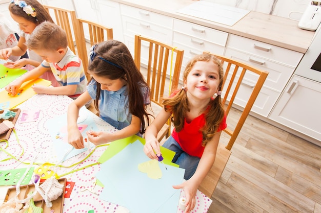 Schattig klein meisje lacht terwijl ze ansichtkaarten maakt met andere kinderen