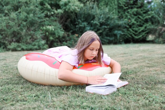 Schattig klein meisje leesboek buitenshuis. Zomerrust