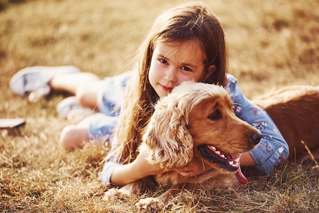 Schattig klein meisje maakt een wandeling met haar hond buiten op een zonnige dag