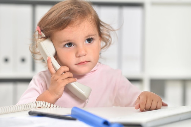 Schattig klein meisje met behulp van telefoon op kantoor