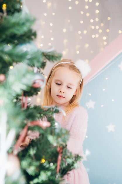 Schattig klein meisje met blond haar is een kerstboom versieren