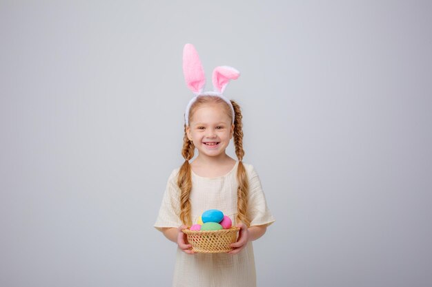 Schattig klein meisje met bunny oren paasei mand op witte achtergrond