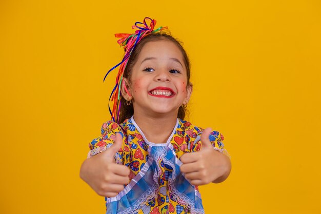 Schattig klein meisje met duim omhoog gekleed in festa junina outfit