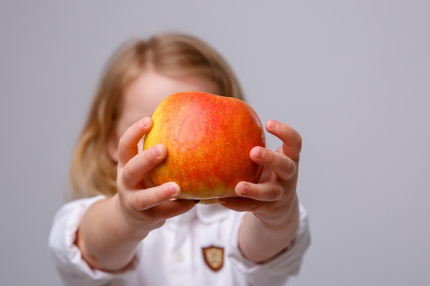 Schattig klein meisje met een appel op een witte achtergrond