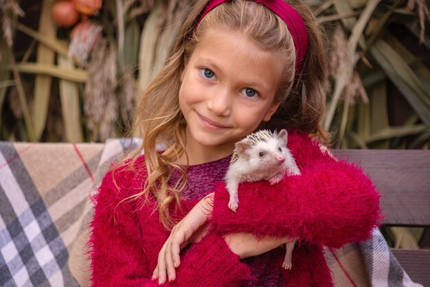 schattig klein meisje met een egel in haar armen herfstportret