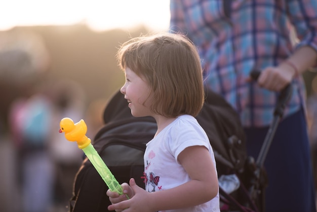 schattig klein meisje met een pop in haar handen in een prachtige bloementuin