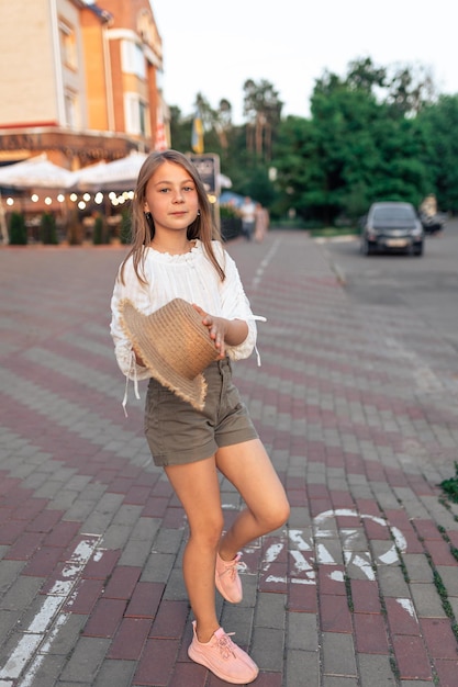 Schattig klein meisje met een strohoed in haar handen geniet van de zomer en het leven