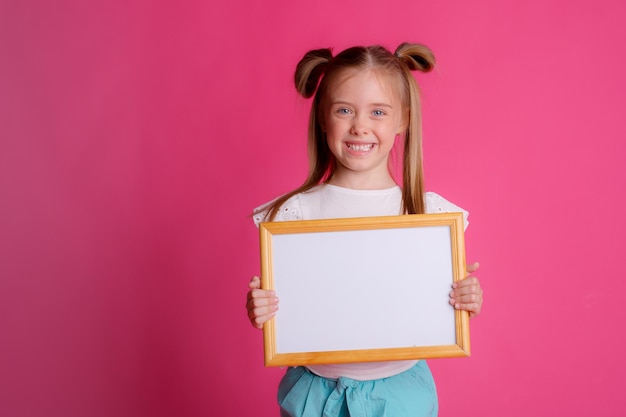 Schattig klein meisje met een wit vel papier op een roze backgroundspace