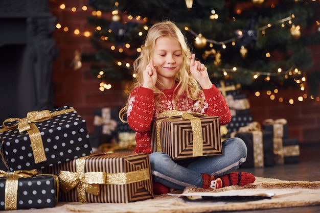 Schattig klein meisje met geschenkdozen binnenshuis vieren nieuwjaar en kerstvakantie.