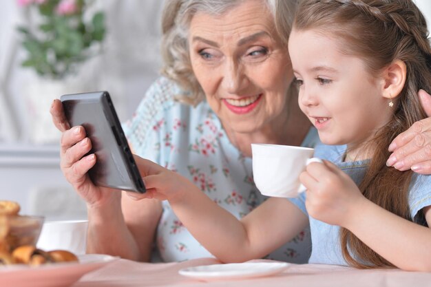 Schattig klein meisje met haar grootmoeder kijken naar tablet