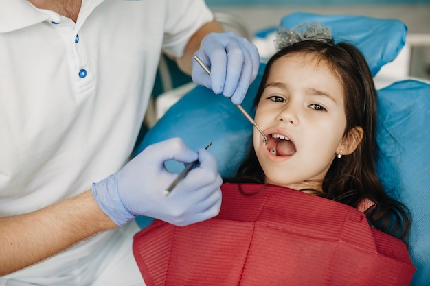 Schattig klein meisje met kiespijn tanden onderzoek bij pediatrische tandarts.