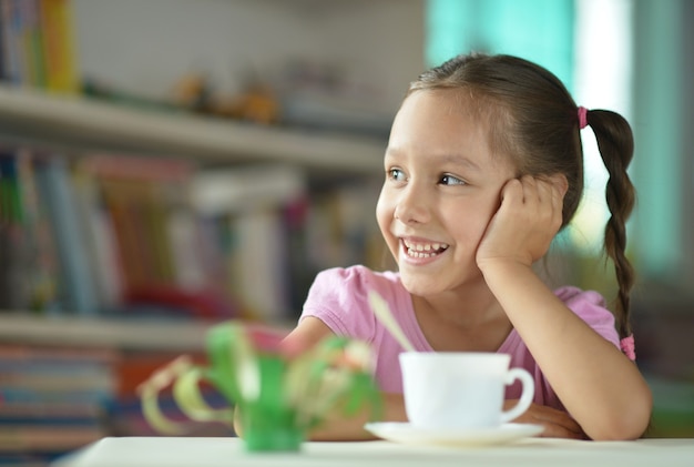 Schattig klein meisje met kopje op tafel