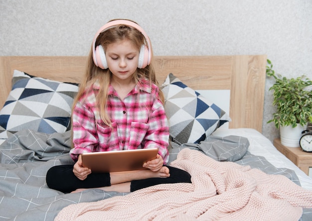 Schattig klein meisje met koptelefoon gebruikt thuis een tablet