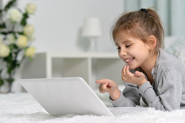 Schattig klein meisje met laptop thuis
