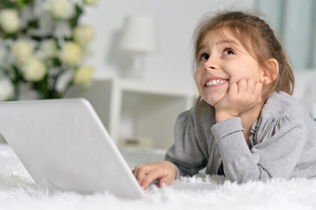 Schattig klein meisje met laptop thuis