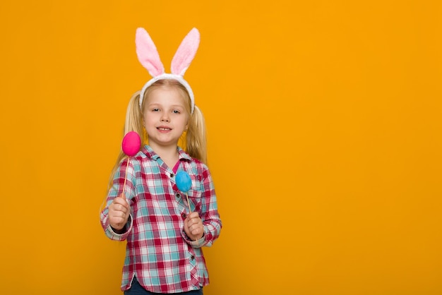 Schattig klein meisje met paashaas oren met kleurrijke eieren