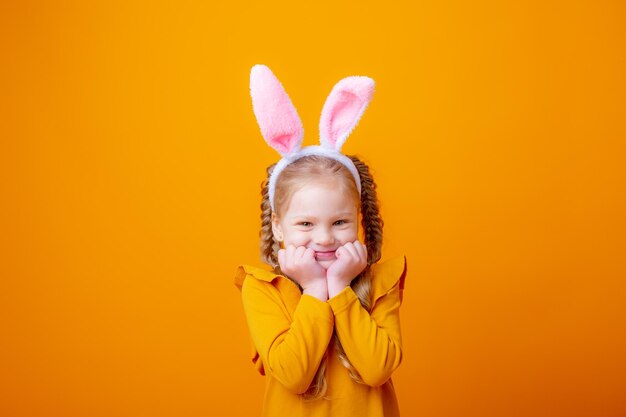 Schattig klein meisje met paashaas oren op een gele achtergrond toont verschillende emoties vreugde dromen