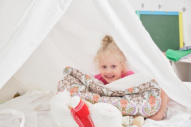 Schattig klein meisje met plezier en spelen in haar tent, Hut in de kinderkamer, activiteiten concept