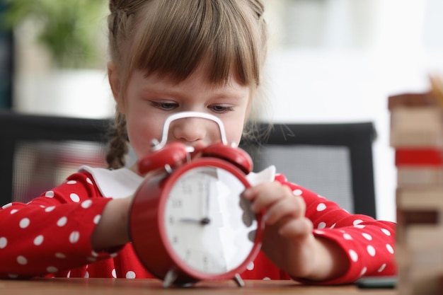 Foto schattig klein meisje met rode wekker