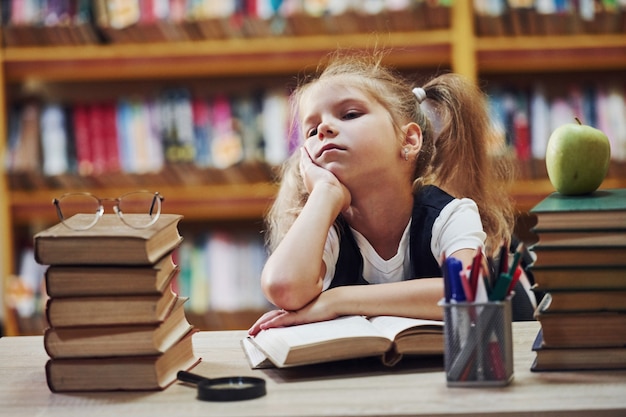 Schattig klein meisje met staartjes is in de bibliotheek