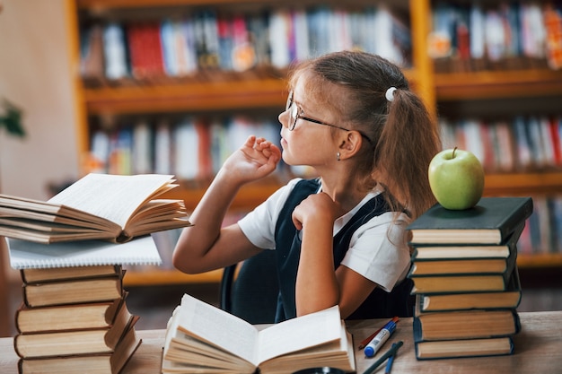 Schattig klein meisje met staartjes is in de bibliotheek