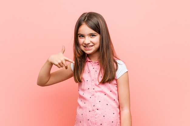 Schattig klein meisje persoon wijst met de hand naar een shirt kopie ruimte, trots en zelfverzekerd