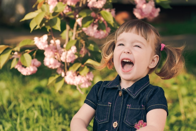 Schattig klein meisje portret in de tuin, sakura bloesem