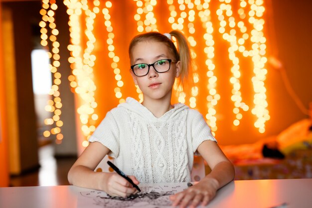 Schattig klein meisje schrijft een brief aan Santa Klaus zittend op de tafel