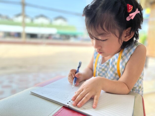 Foto schattig klein meisje schrijft op haar notitieboekje