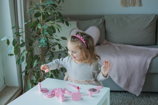 Schattig klein meisje speelt in een schoonheidssalon Mooi meisje van 3 jaar maakt thuis make-up met kindercosmetica