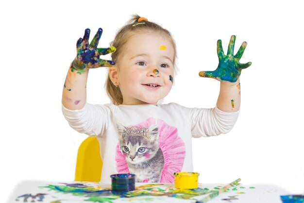 Schattig klein meisje speelt met gekleurde verf op een witte achtergrond