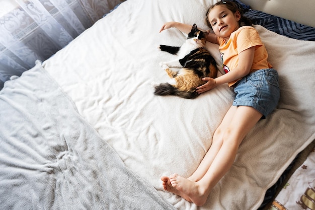 Schattig klein meisje speelt met haar kat op het bed thuis