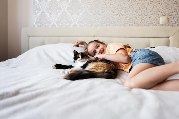 Schattig klein meisje speelt met haar kat op het bed thuis