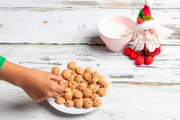 Schattig klein meisje speelt met kerstkoekjes en melk met Kerstmis