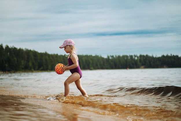 Schattig klein meisje speelt met rubberen bal in zee