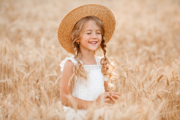 Schattig klein meisje speelt op een tarweveld op een warme zomerdag