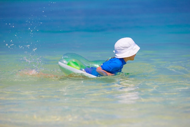 Schattig klein meisje spelen in ondiep water op witte strand