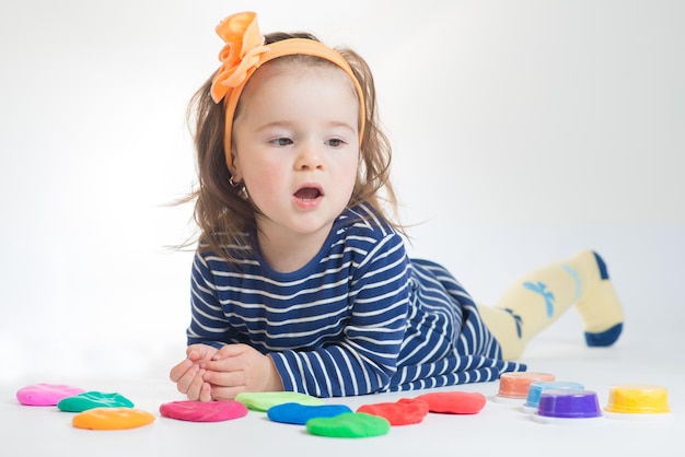 Schattig klein meisje spelen met gekleurde plasticine op een witte achtergrond