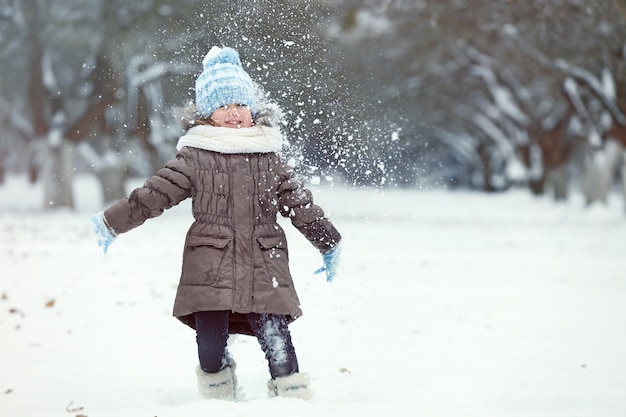 Schattig klein meisje spelen met sneeuw in winter park